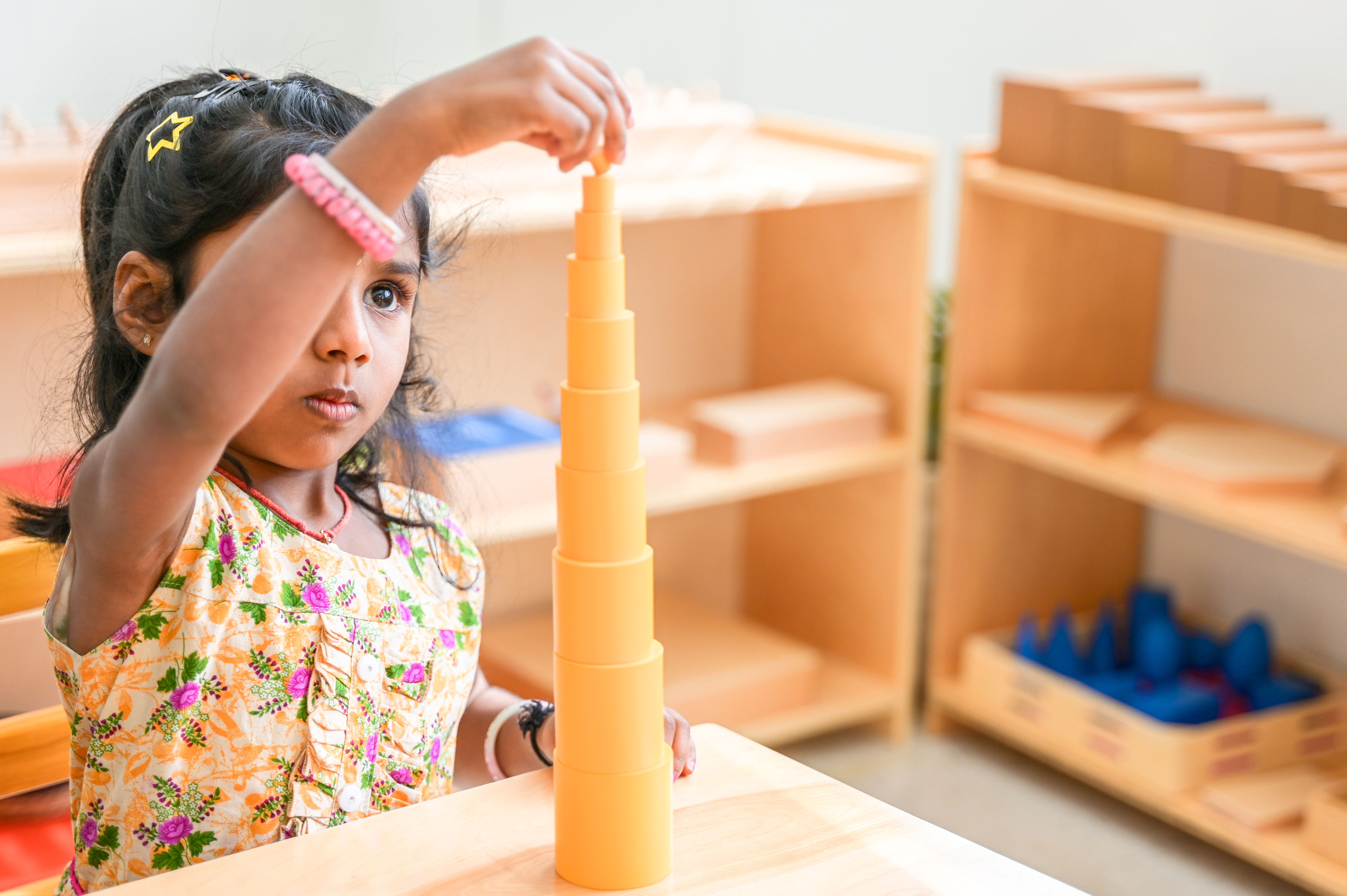 Child building tower of cylinders at camp