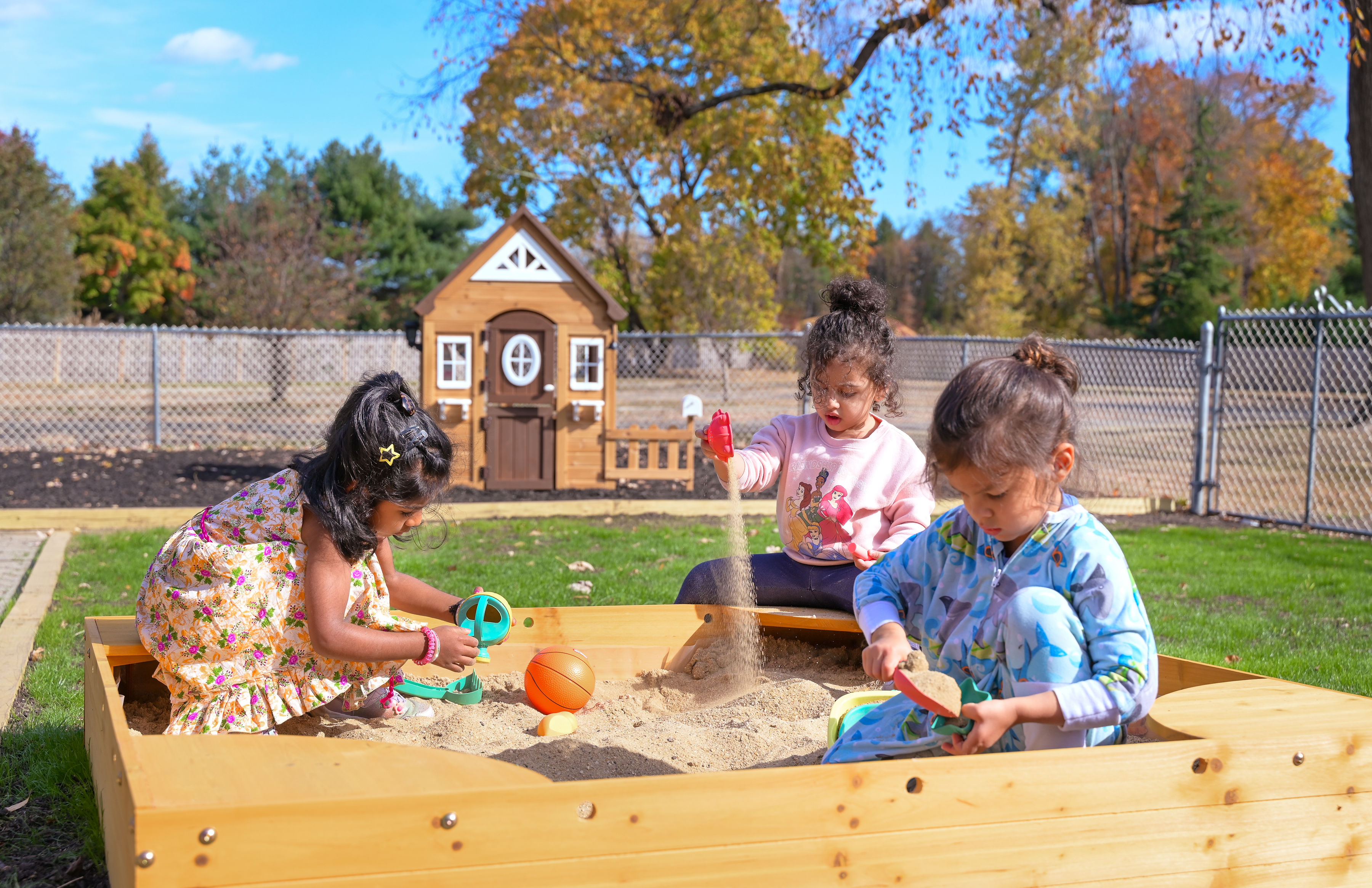 Children playing in sandbox with playhouse
